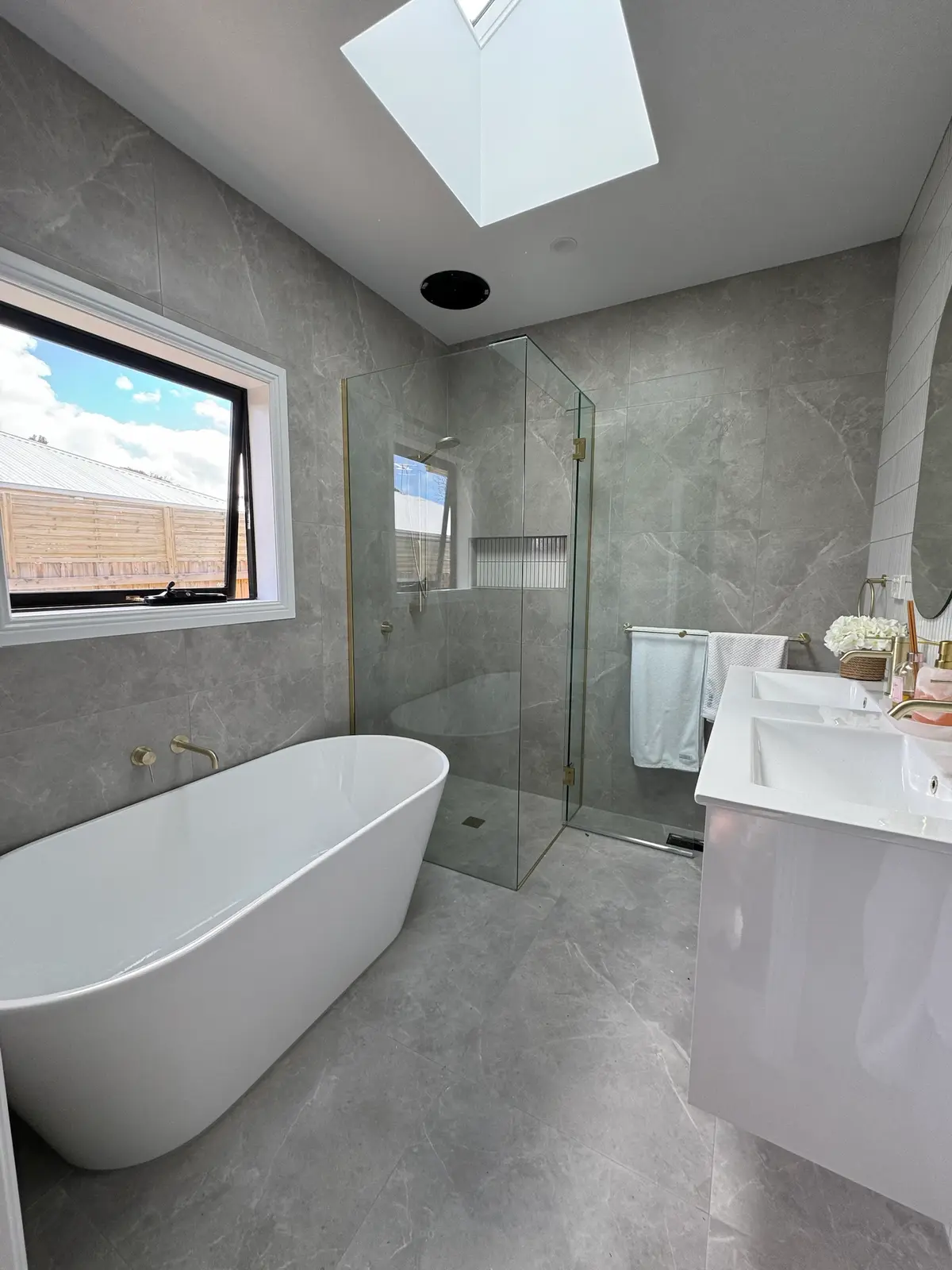 Renovated bathroom with freestanding bath, frameless corner shower, double vanity and a skylight in the ceiling