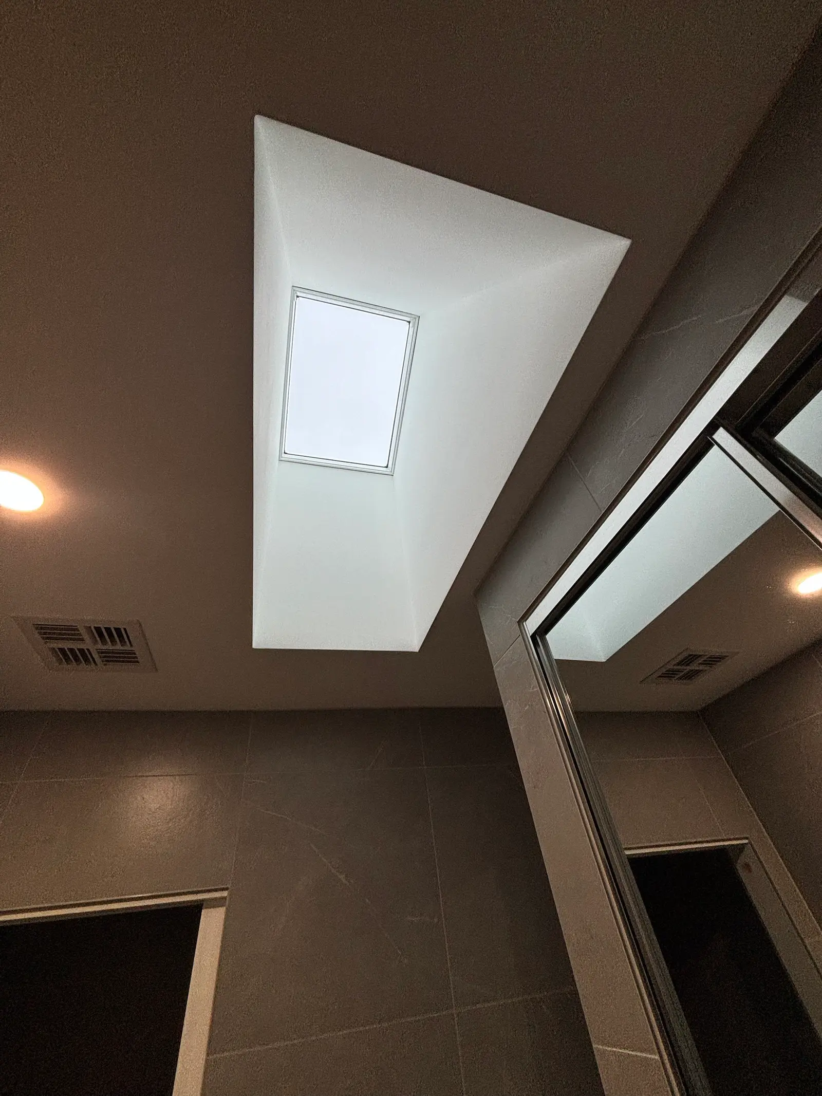Looking up at the skylight through its splayed, white-plastered light shaft in the powder room ceiling